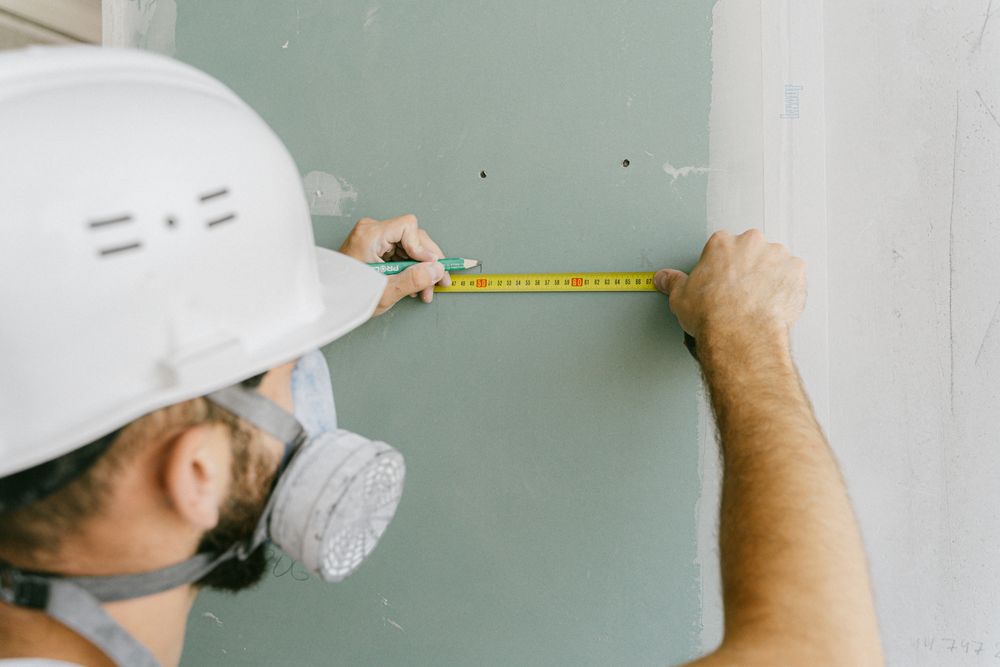 Professional measuring plasterboard during interior installation