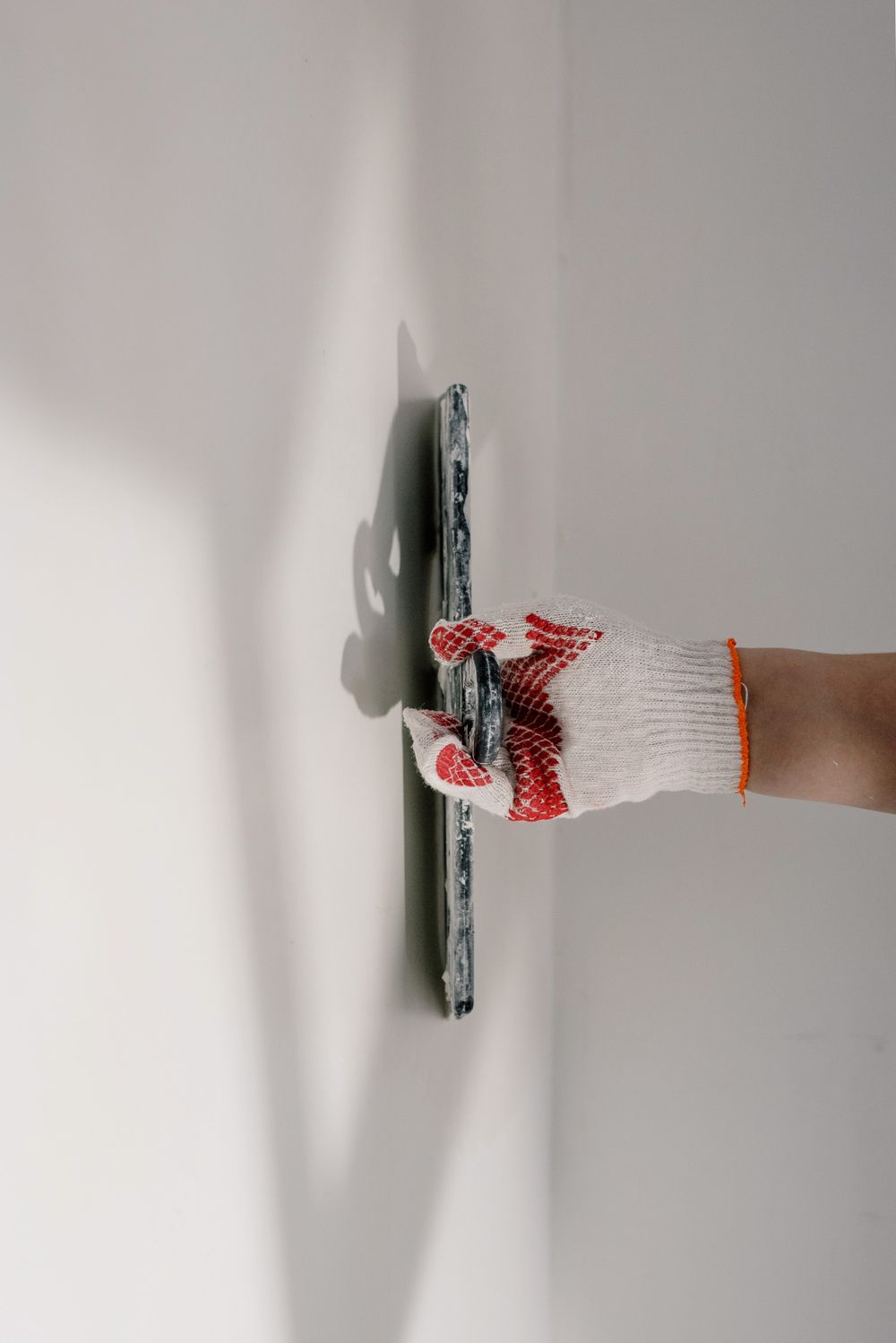Gloved hand smoothing a fine plaster finish with a trowel